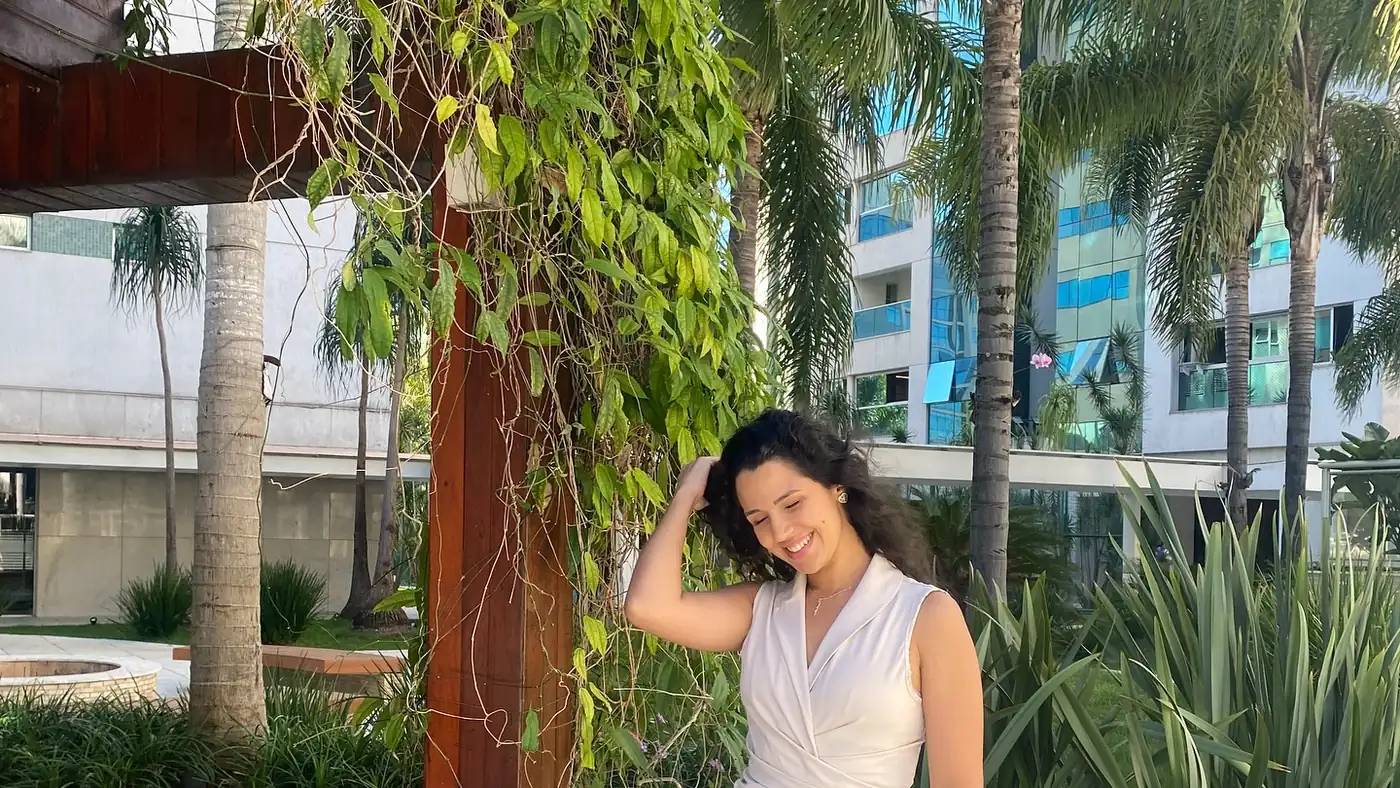 Viviane Bastos em um jardim, de vestido claro
